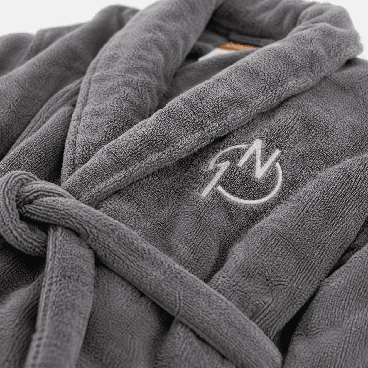 Grauer Frottee-Bademantel mit rundem Monogramm-Logo auf der Brust bestickt